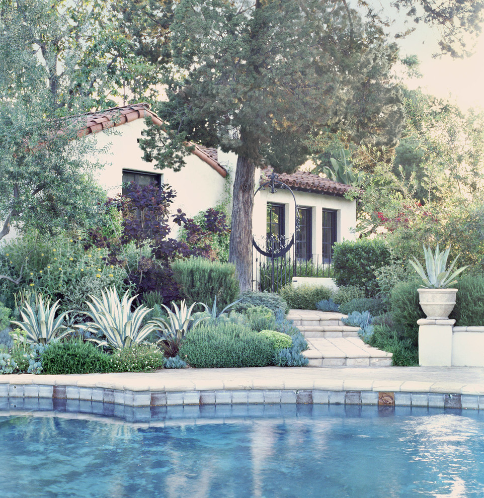 На фото: большой регулярный сад на заднем дворе в средиземноморском стиле с полуденной тенью и мощением тротуарной плиткой