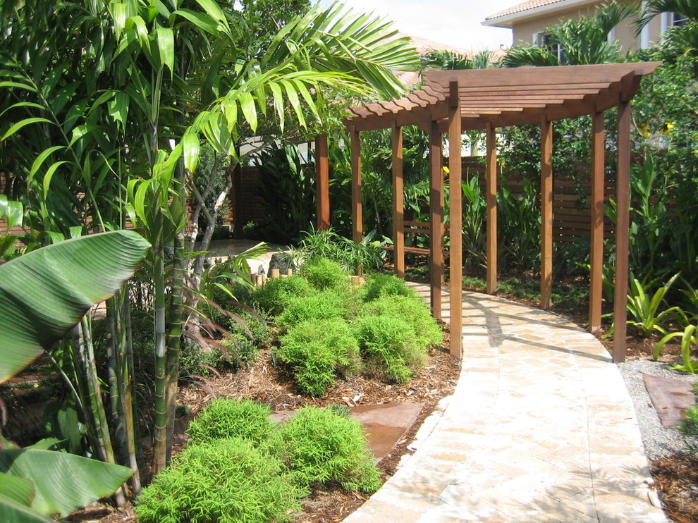 Exemple d'un aménagement d'entrée ou allée de jardin latéral exotique de taille moyenne et l'été avec une exposition partiellement ombragée et des pavés en pierre naturelle.