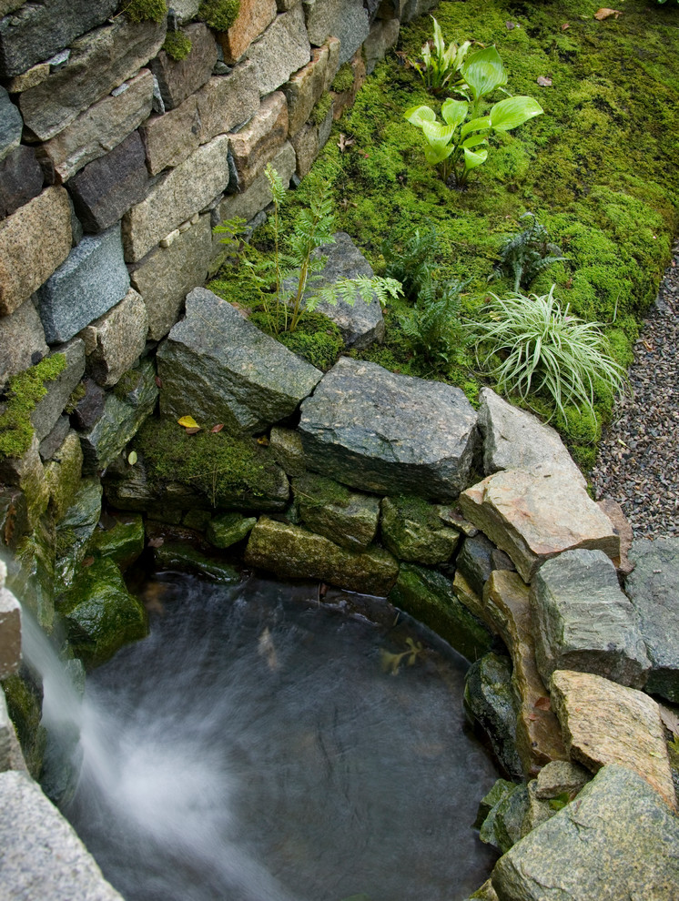 Imagen de jardín rústico de tamaño medio en patio trasero con fuente y adoquines de piedra natural