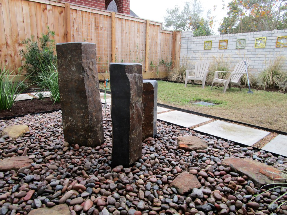 This is an example of a medium sized modern courtyard full sun garden in Houston with gravel and a water feature.