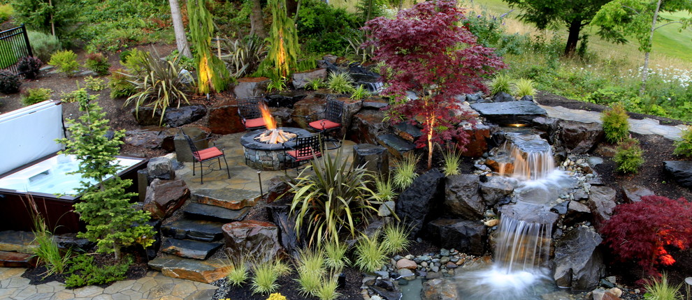 Diseño de jardín exótico de tamaño medio en patio trasero con jardín francés, fuente y adoquines de piedra natural