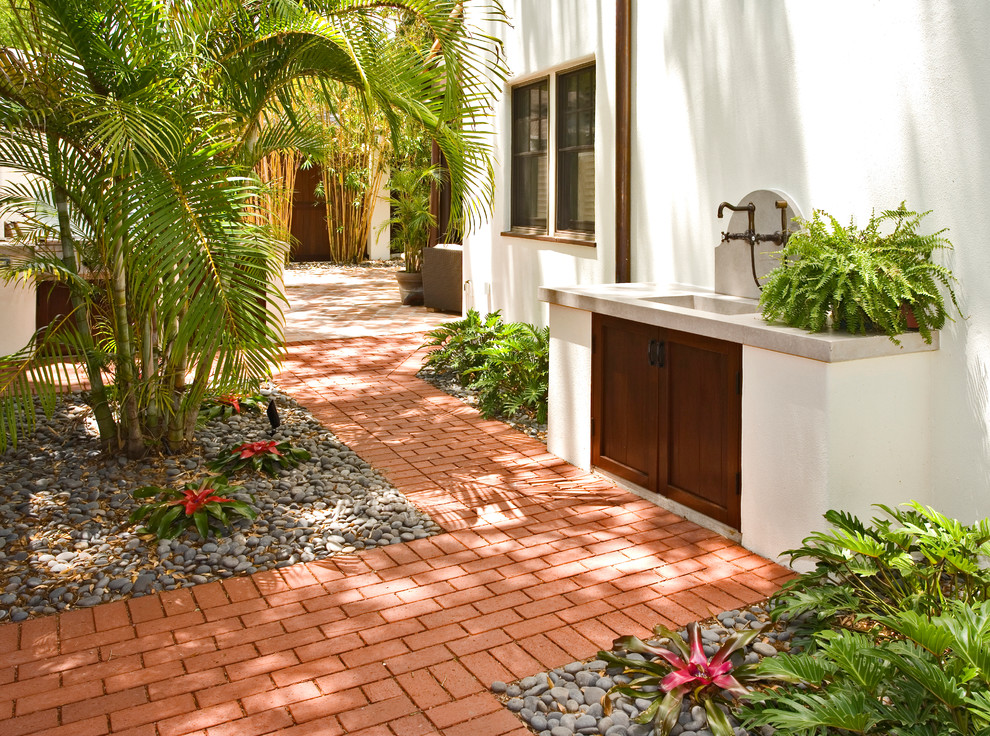 Kleiner, Halbschattiger Mediterraner Garten im Sommer, hinter dem Haus mit Pflastersteinen in Tampa