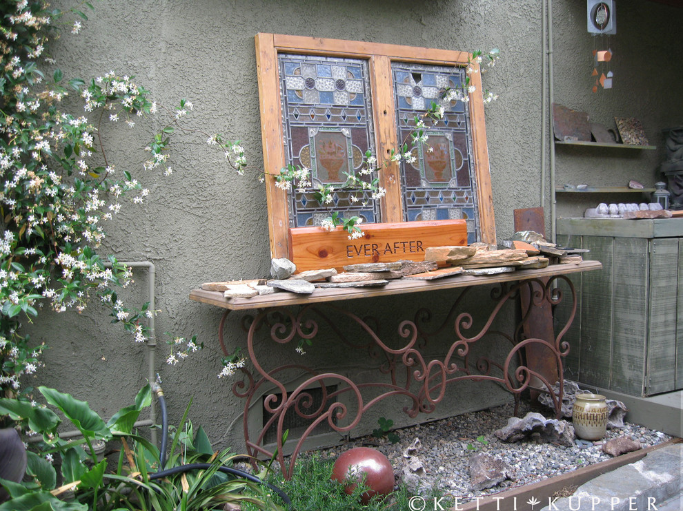 Idéer för en liten eklektisk formell trädgård i delvis sol längs med huset på våren, med en trädgårdsgång och marksten i betong