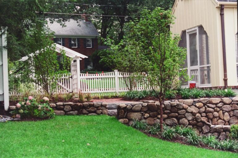 Design ideas for a mid-sized traditional shade hillside stone retaining wall landscape in Boston.