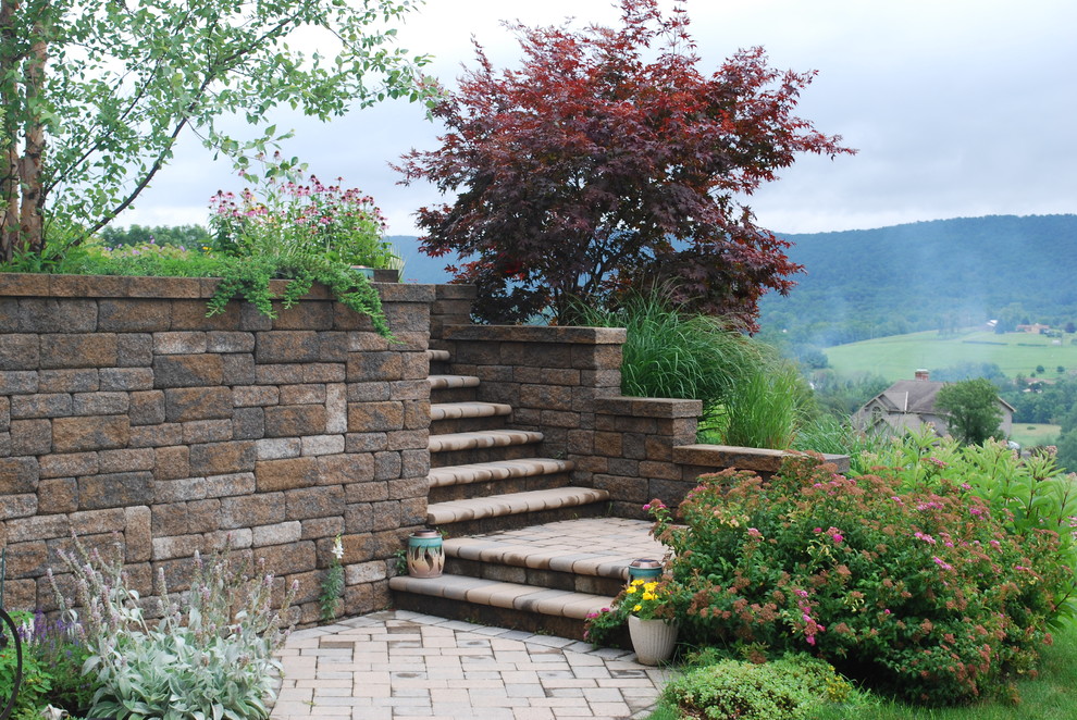 Foto di un giardino classico esposto in pieno sole in estate con un muro di contenimento, un pendio, una collina o una riva e pavimentazioni in pietra naturale