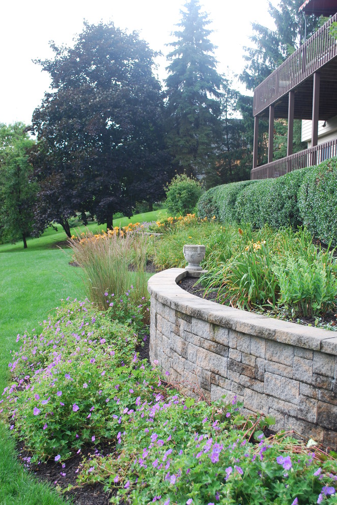Esempio di un grande giardino classico esposto in pieno sole dietro casa in estate con un muro di contenimento e pavimentazioni in cemento