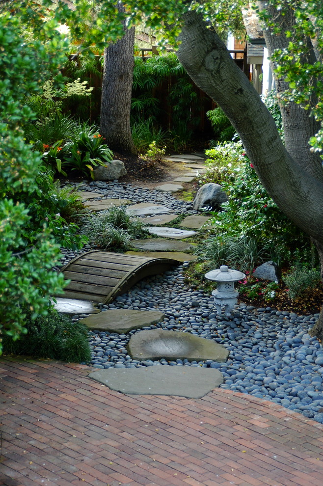 This is an example of a traditional shade backyard river rock water fountain landscape in San Francisco.