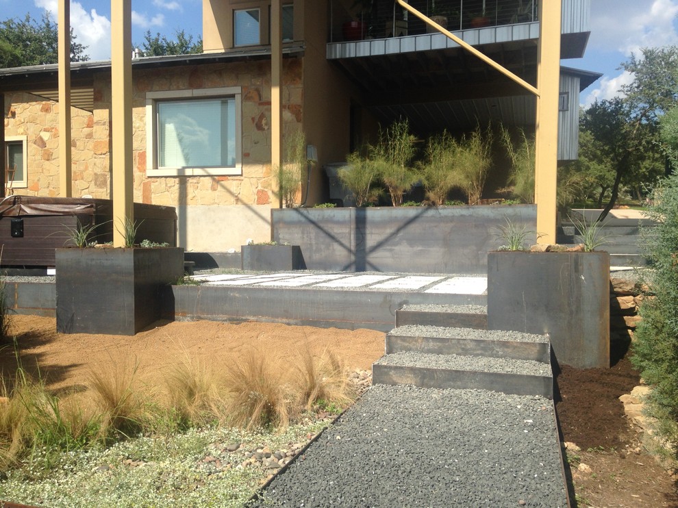 Imagen de jardín de secano minimalista de tamaño medio en verano en patio trasero con muro de contención, exposición parcial al sol y adoquines de piedra natural