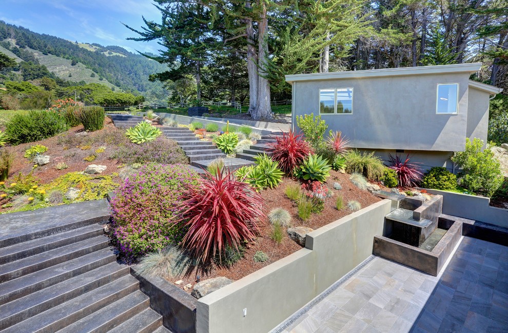Diseño de jardín contemporáneo grande en verano en patio lateral con muro de contención, exposición total al sol y adoquines de piedra natural