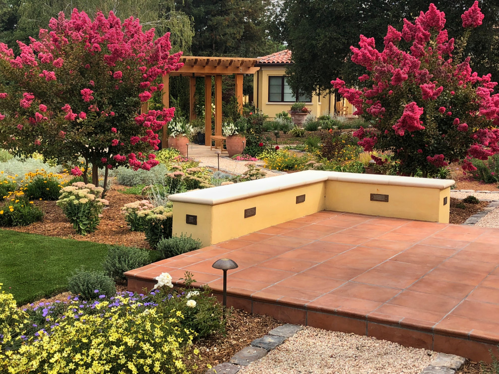 Immagine di un ampio giardino mediterraneo esposto in pieno sole dietro casa in estate con ghiaia