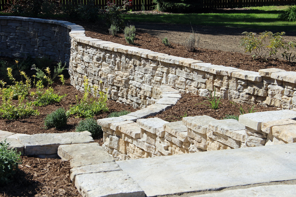 Photo of a mid-sized traditional partial sun backyard stone landscaping in Other for summer.