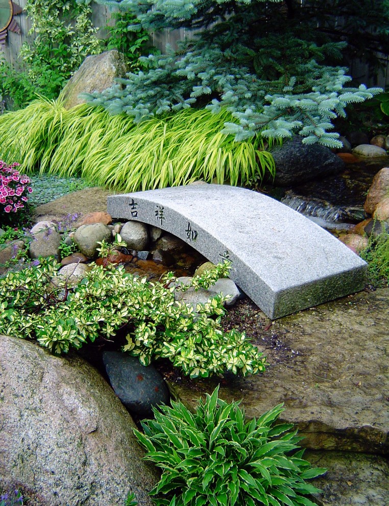 Exempel på en mellanstor asiatisk bakgård, med en fontän och naturstensplattor
