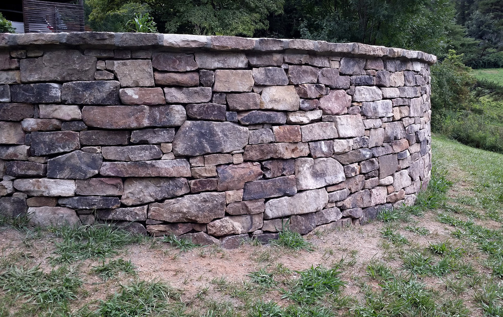 Aménagement d'un jardin arrière montagne avec un mur de soutènement et des pavés en pierre naturelle.