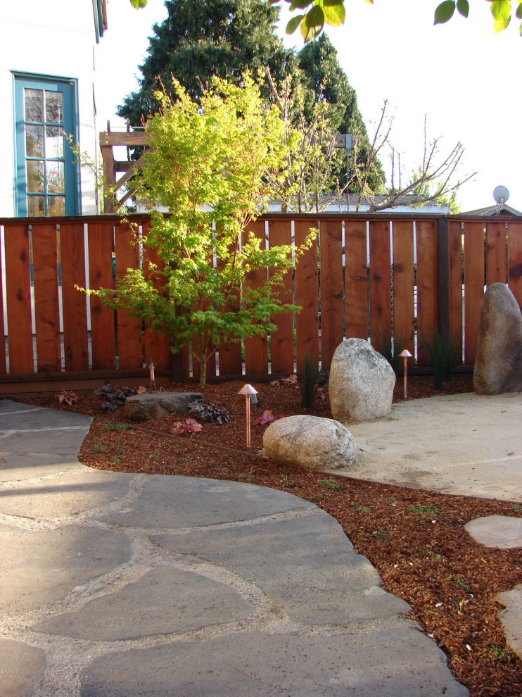 Cette image montre un jardin arrière asiatique avec pierres et graviers, des pavés en pierre naturelle et une clôture en bois.