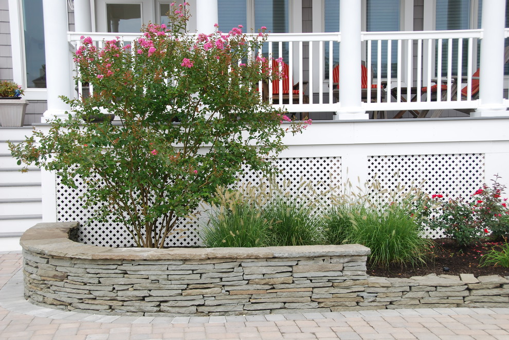 Inspiration for a nautical front partial sun garden for summer in New York with a retaining wall and natural stone paving.
