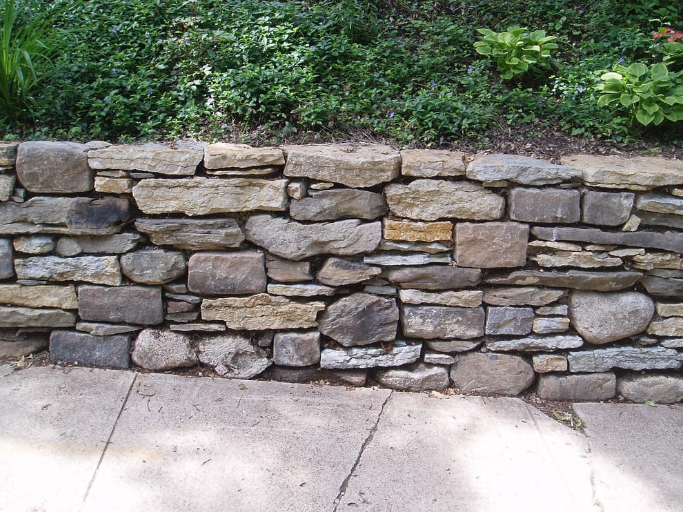 Réalisation d'un jardin latéral chalet de taille moyenne avec un mur de soutènement et des pavés en pierre naturelle.