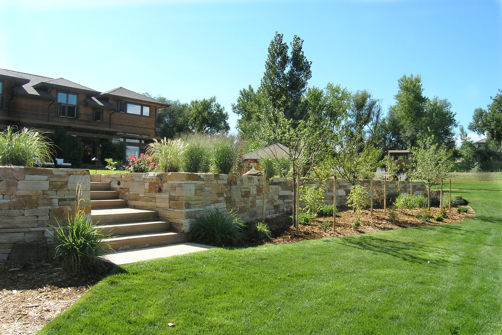 Idee per un grande giardino formale stile rurale esposto in pieno sole dietro casa in primavera con un muro di contenimento e pacciame