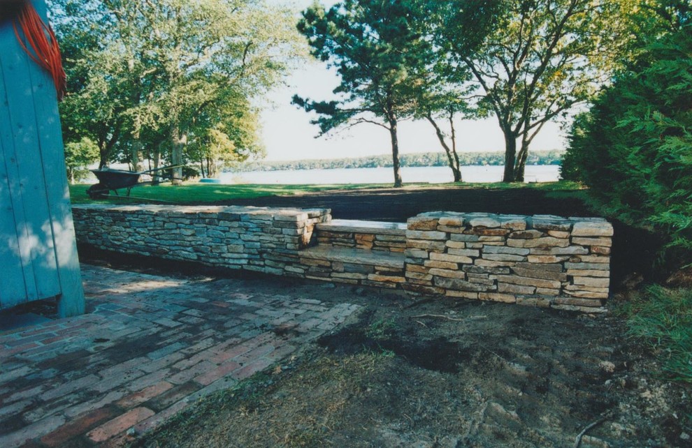 Cette image montre un jardin arrière chalet de taille moyenne avec un mur de soutènement et des pavés en pierre naturelle.