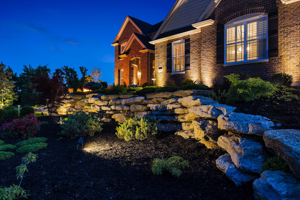 Photo of a mid-sized modern drought-tolerant and full sun front yard stone retaining wall landscape in St Louis for summer.