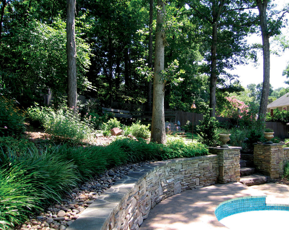 Esempio di un grande giardino boho chic dietro casa con un muro di contenimento e pavimentazioni in pietra naturale