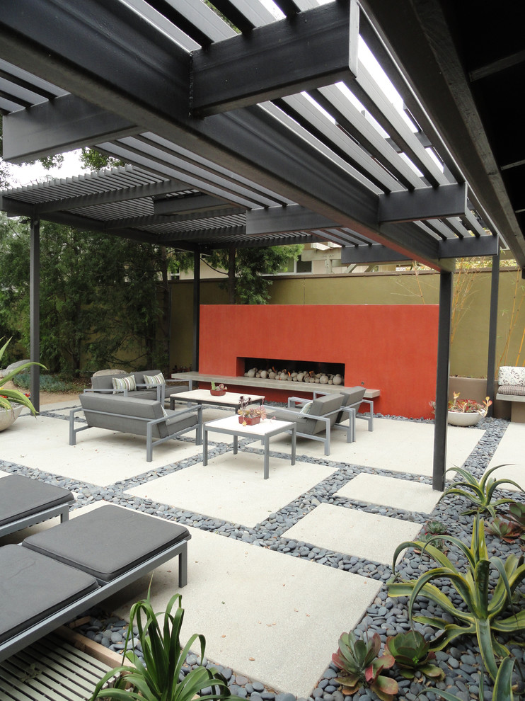 Esempio di un patio o portico moderno di medie dimensioni e dietro casa con un focolare e pavimentazioni in cemento