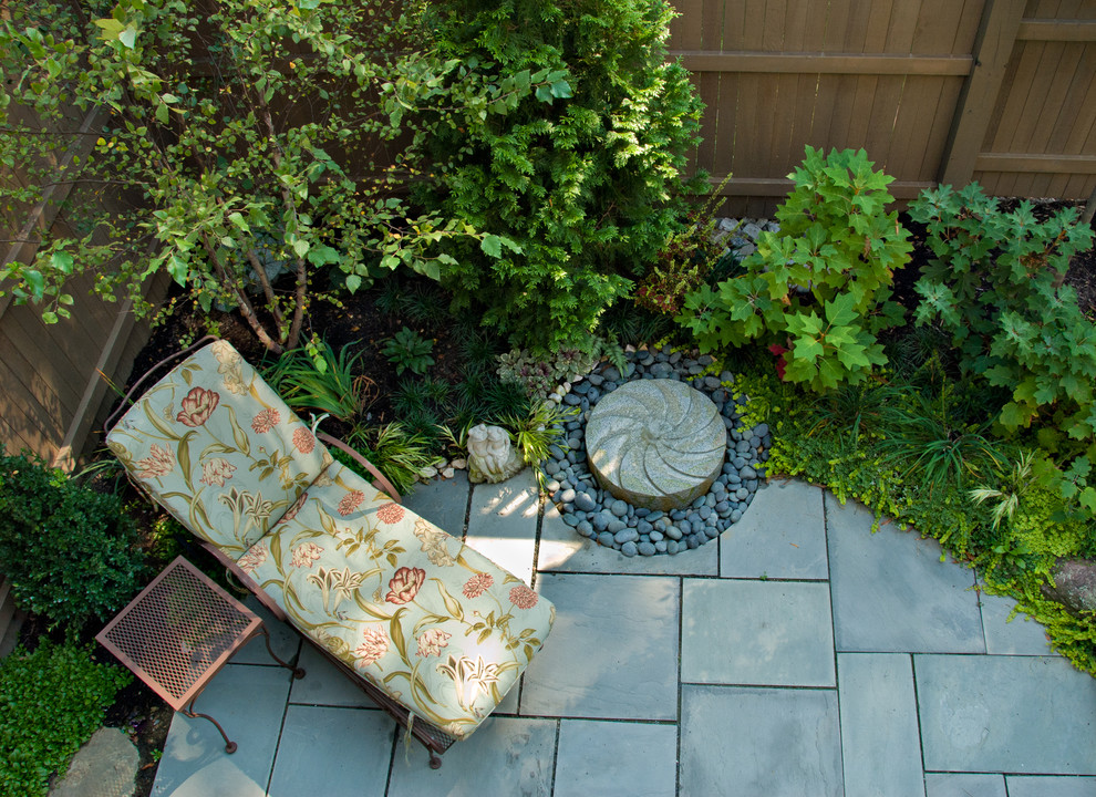 Imagen de jardín ecléctico pequeño en verano en patio trasero con jardín francés, fuente, exposición parcial al sol y adoquines de piedra natural