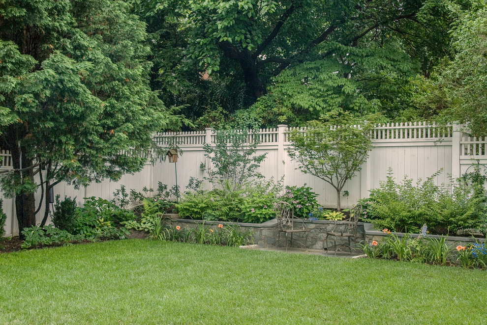Immagine di un piccolo giardino formale classico esposto a mezz'ombra dietro casa in estate con un muro di contenimento e pavimentazioni in pietra naturale