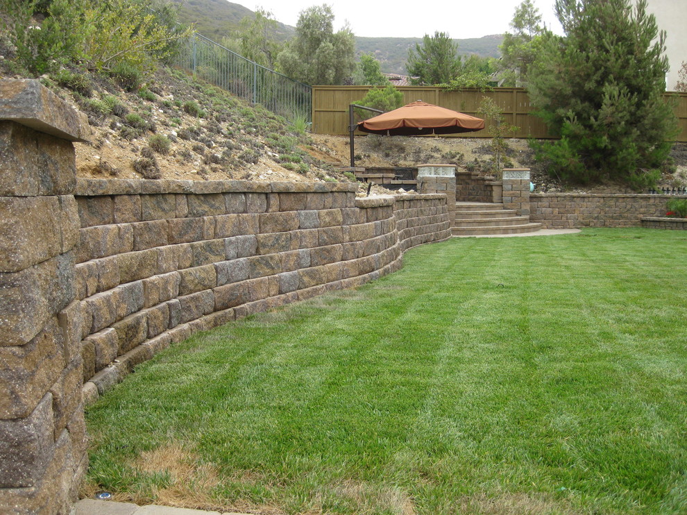Immagine di un giardino di medie dimensioni e dietro casa con un muro di contenimento e pavimentazioni in cemento