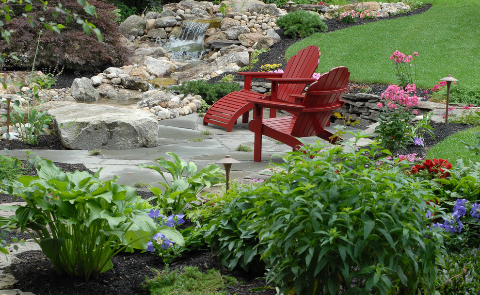 Imagen de jardín tradicional de tamaño medio en verano en patio trasero con jardín francés, adoquines de piedra natural y estanque