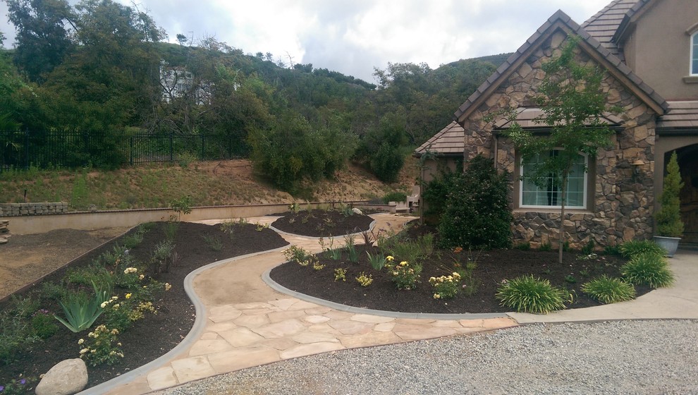 Immagine di un grande giardino xeriscape mediterraneo esposto in pieno sole davanti casa con pavimentazioni in pietra naturale
