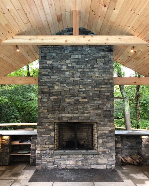 This is an example of a contemporary back partial sun garden for summer in New York with a fireplace and natural stone paving.