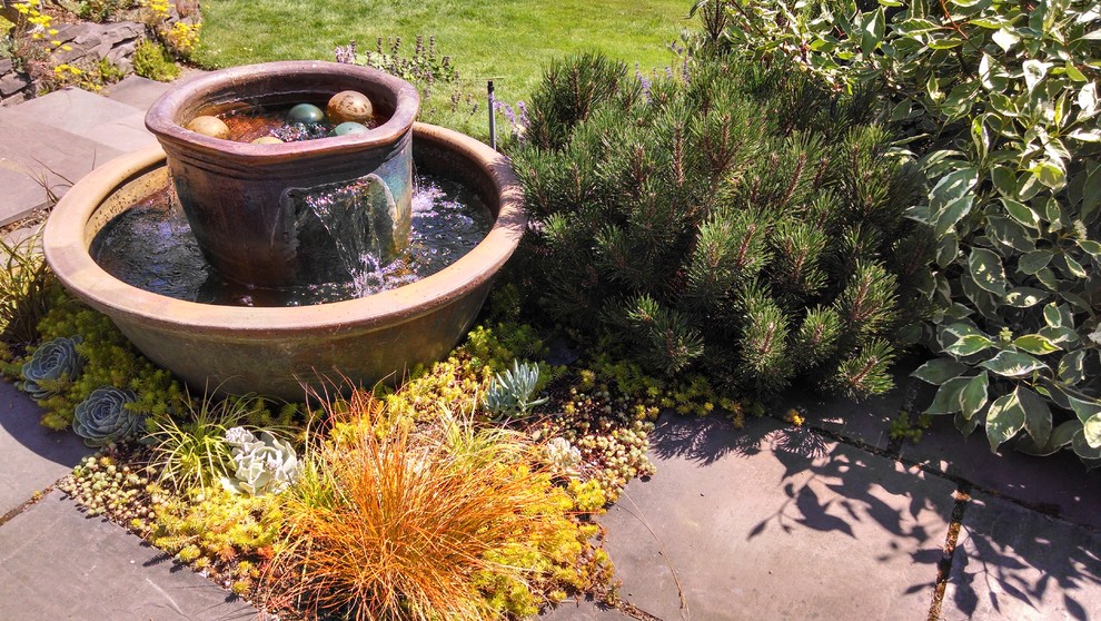 Immagine di un ampio giardino formale mediterraneo esposto in pieno sole dietro casa in estate con fontane e pavimentazioni in pietra naturale