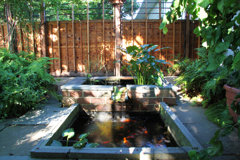 Imagen de jardín actual pequeño en verano en patio con fuente, exposición reducida al sol, adoquines de piedra natural y jardín francés