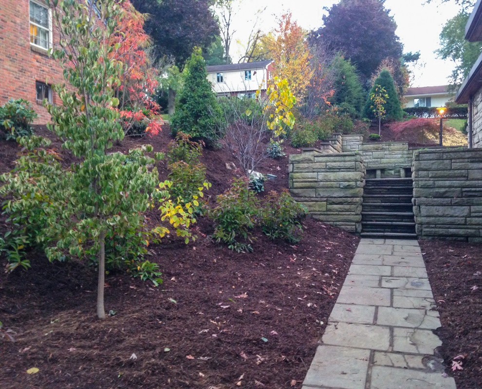 Photo of an expansive classic side formal full sun garden for autumn in Other with a retaining wall and natural stone paving.