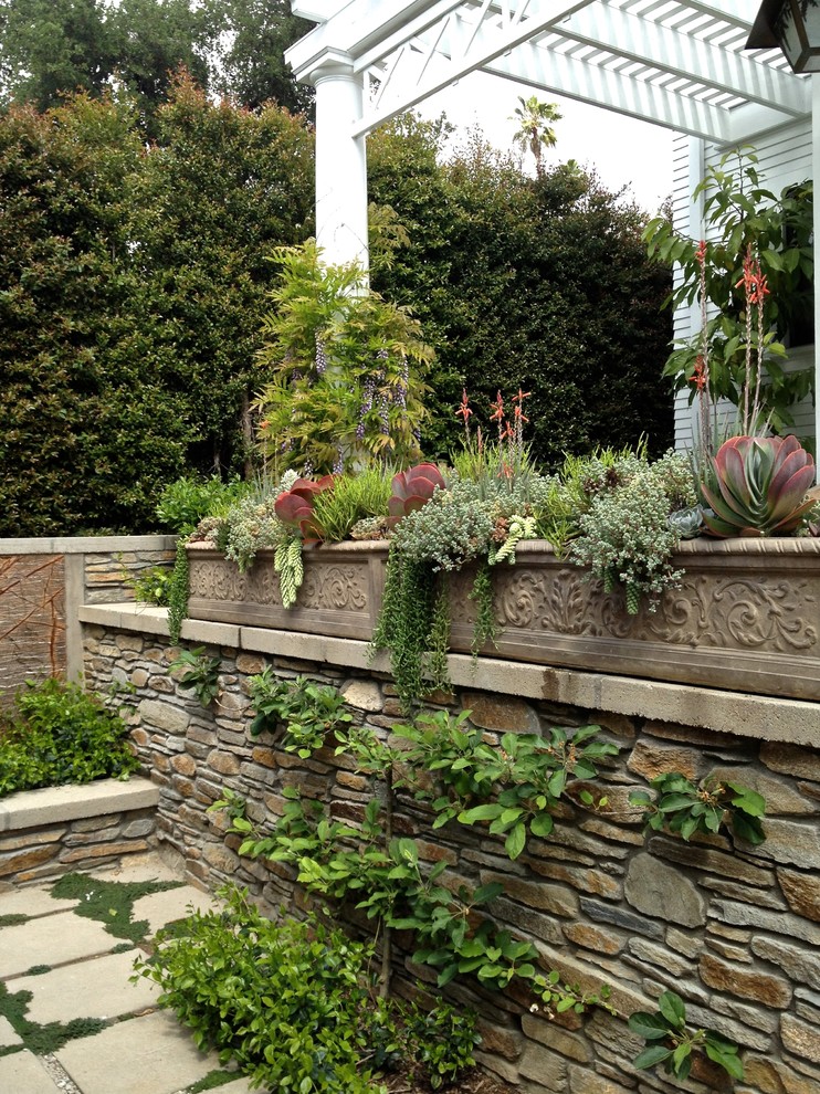 На фото: участок и сад в средиземноморском стиле с растениями в контейнерах и покрытием из каменной брусчатки с