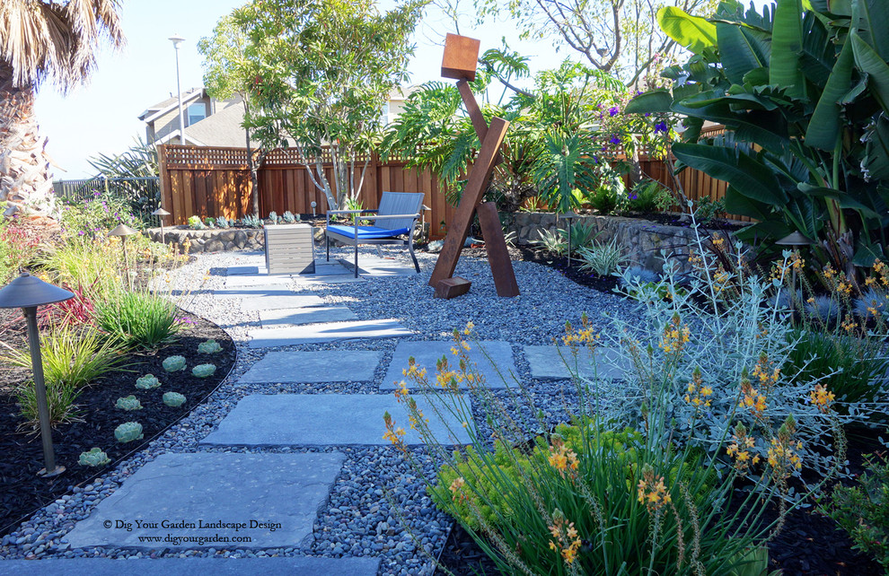 Diseño de jardín de secano actual de tamaño medio en primavera en patio lateral con exposición parcial al sol y adoquines de piedra natural