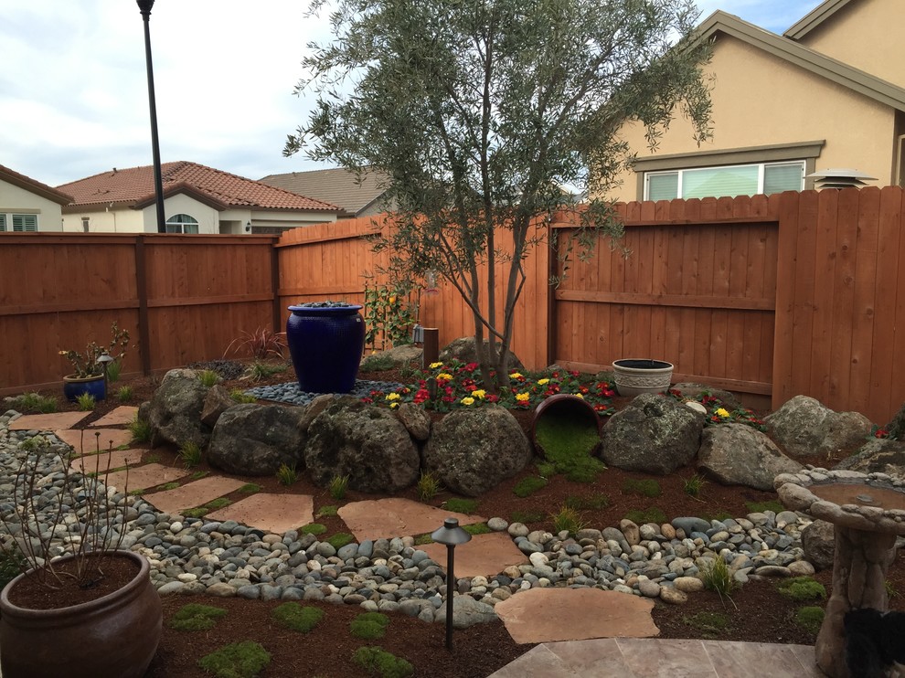 Foto de jardín de estilo americano de tamaño medio en patio trasero con fuente, exposición total al sol y adoquines de piedra natural