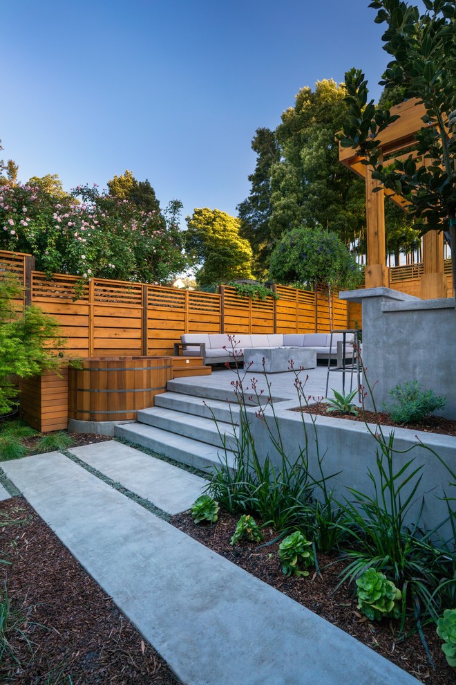 Kleiner Moderner Garten hinter dem Haus mit Feuerstelle, direkter Sonneneinstrahlung und Betonboden in San Francisco