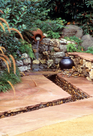 Ejemplo de jardín de secano rural de tamaño medio en verano en patio con fuente, adoquines de piedra natural y exposición total al sol