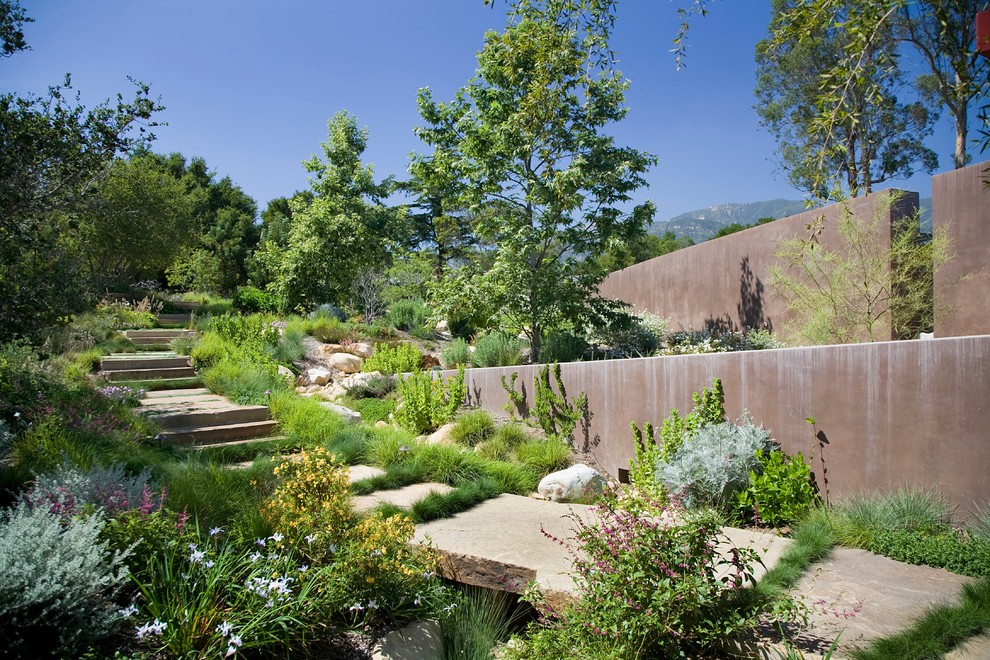 Inredning av en modern trädgård, med en stödmur och naturstensplattor