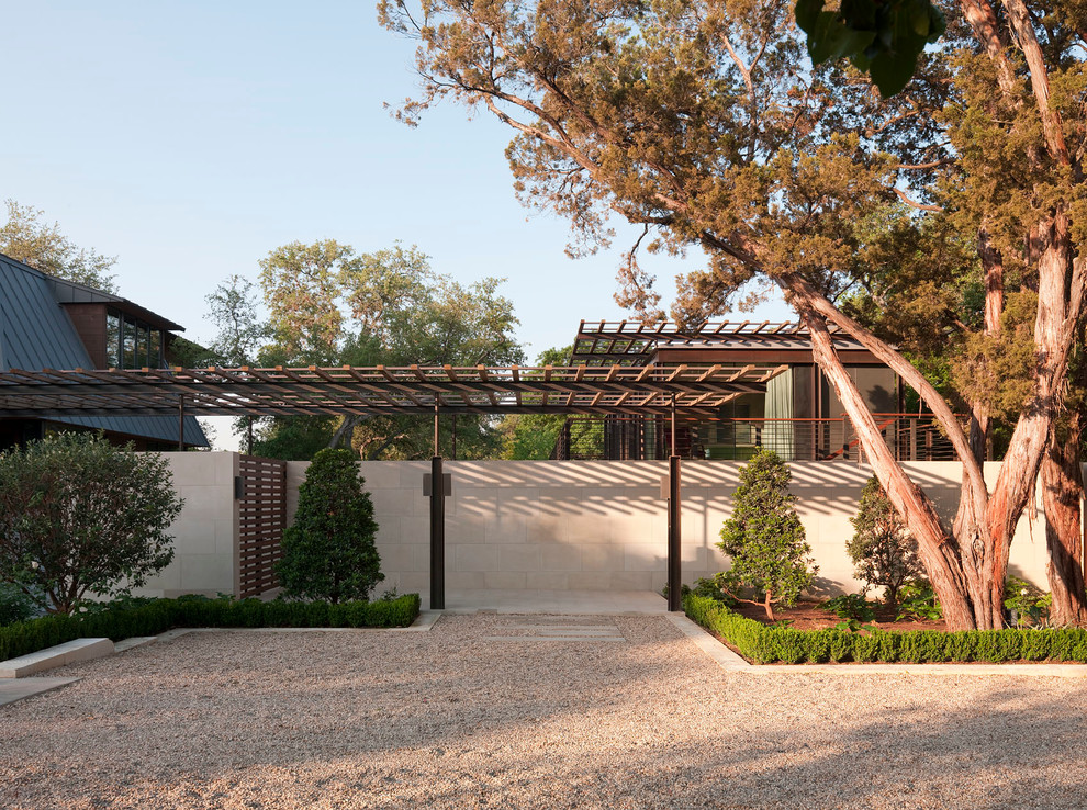 Large modern back formal partial sun garden in Austin with gravel.