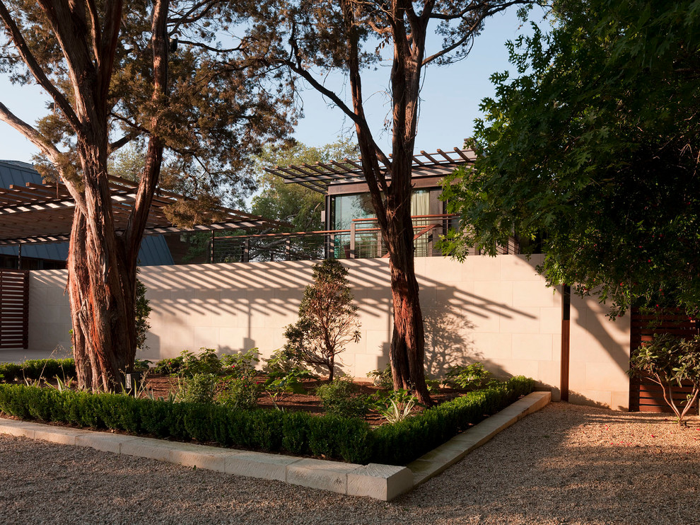 Réalisation d'un grand jardin à la française arrière minimaliste avec une exposition partiellement ombragée et du gravier.