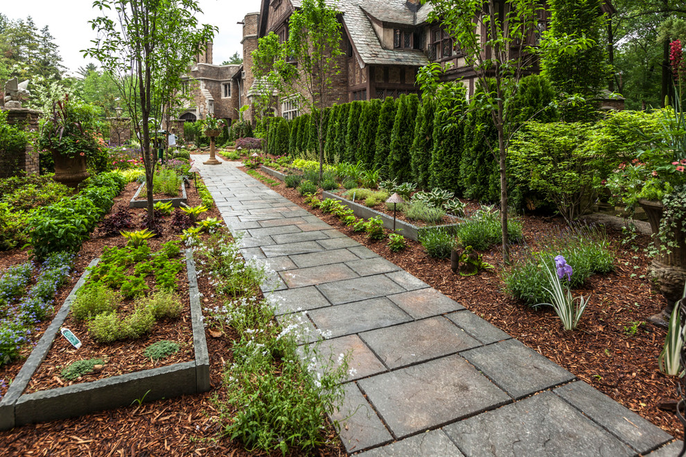 Пример оригинального дизайна: большой солнечный, весенний регулярный сад на переднем дворе в классическом стиле с садовой дорожкой или калиткой, хорошей освещенностью и покрытием из каменной брусчатки