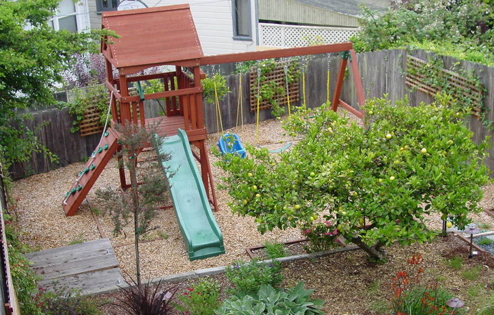Idee per un piccolo giardino xeriscape vittoriano esposto a mezz'ombra dietro casa in estate con uno spazio giochi e ghiaia