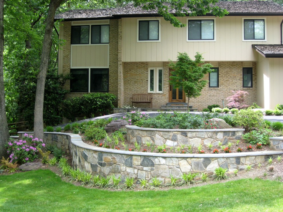 Modelo de jardín clásico de tamaño medio en patio delantero con jardín francés, muro de contención, exposición parcial al sol y adoquines de piedra natural
