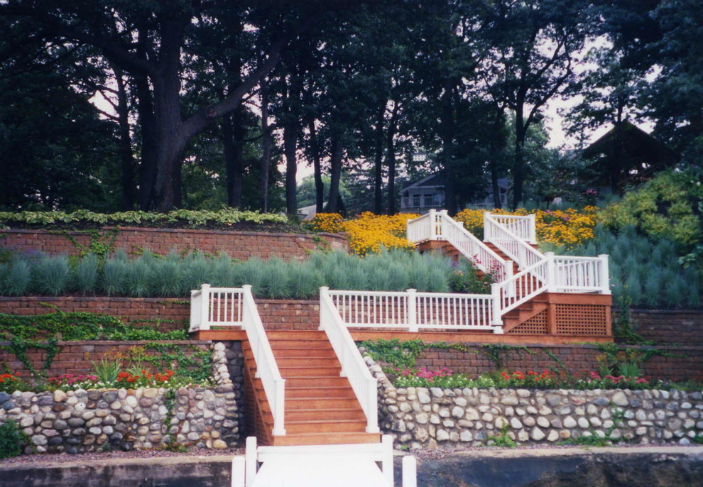 Cette image montre un jardin traditionnel l'été avec un mur de soutènement, une exposition partiellement ombragée, une pente, une colline ou un talus et des pavés en pierre naturelle.