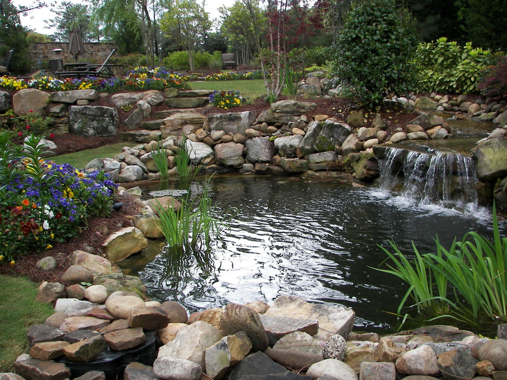 This is an example of an expansive traditional back fully shaded garden in Atlanta with a pond and natural stone paving.