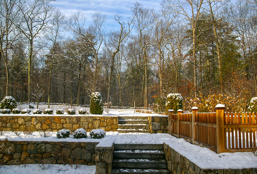 This is an example of a mid-sized traditional partial sun backyard stone retaining wall landscape in Boston for winter.