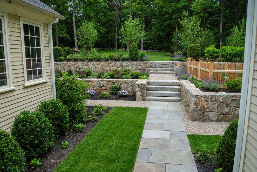Ejemplo de jardín tradicional de tamaño medio en patio trasero con muro de contención