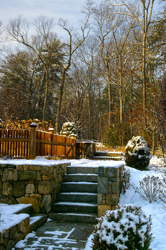 Imagen de jardín tradicional de tamaño medio en invierno en patio trasero con muro de contención, exposición total al sol y adoquines de piedra natural